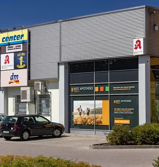 Außenansicht der Apotheke Augsburg neben dem EDEKA Center mit gut sichtbarem Apotheken-Schild.