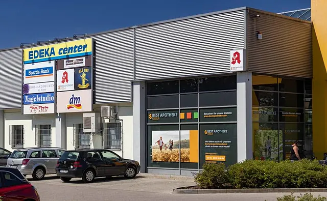 Außenansicht der Apotheke Augsburg neben dem EDEKA Center mit gut sichtbarem Apotheken-Schild.